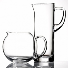 Simple, fluid glass forms with thick shams and hand cut polished edges. A sleek collection of pitchers for entertaining or everyday use. Lead free. Handwashing recommended. Shown from left to right: clear round pitcher, tall glass pitcher. Also available but not shown: Tula curved pitcher. Simple, fluid glass forms with thick shams and hand cut polished edges. A sleek collection of pitchers for entertaining or everyday use. Lead free. Handwashing recommended. Shown from left to right: clear round pitcher, tall glass pitcher. Also available but not shown: Tula curved pitcher.
