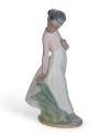 Stopping to smell and pick flowers, a beautiful young girl enjoys a breezy spring day in this delicately glazed figurine from Lladro.