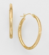 Slim 14k gold hoop earrings have delicate engravings and a high polish for extra shine. Oval-shaped. Wire-catch closure. For pierced ears only.