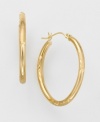 Slim 14k gold hoop earrings have delicate engravings and a high polish for extra shine. Oval-shaped. Wire-catch closure. For pierced ears only.