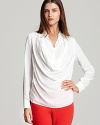 This Calvin Klein blouse stuns with decadent draping, exposing a classic button placket and crisp cuffs for an elevated approach to the essential white shirt.