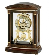 A regal finishing touch for the mantel. This solid wood clock by Bulova is finished in dark wine and features an ornate gold tone dial and gears covered by a glass lens.