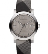 This Burberry watch features a check fabric strap and round stainless steel case. Beige sunray dial with silvertone stick indices, logo and date window. Swiss made. Quartz movement. Water resistant to 50 meters. Two-year limited warranty.