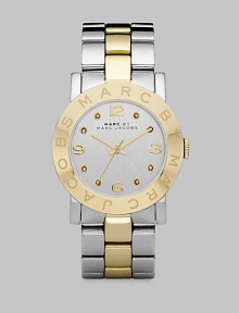 A sleek timepiece with a logo etched bezel and dazzling crystal markers. Quartz movementWater resistant to 5 ATMRound stainless steel case, 36mm (1.4) Logo etched goldtone ion-plated bezelSilver dialCrystal and numeric hour markersSecond hand Two-tone stainless steel link braceletImported A sleek timepiece with a logo etched bezel and dazzling crystal markers. Quartz movementWater resistant to 5 ATMRound stainless steel case, 36mm (1.4) Logo etched goldtone ion-plated bezelSilver dialCrystal and numeric hour markersSecond hand Two-tone stainless steel link braceletImported
